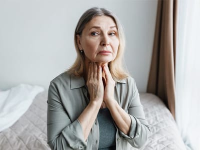 A woman sitting on a bed with a concerned expression