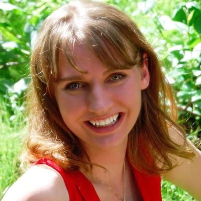 Smiling woman outdoors with greenery in background