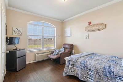 A cozy resident room with a bed and chair
