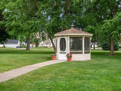 Outdoor gazebo in a grassy area surrounded by trees