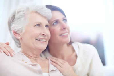 A senior resident and staff member smiling together
