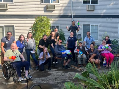 Residents and staff enjoying a water gun fight in the garden