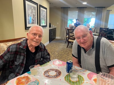 Two residents smiling at a table in a common area