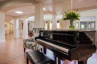 Interior view of a common area with a piano and flowers