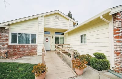 Exterior view of a senior care facility with ramp and flowers
