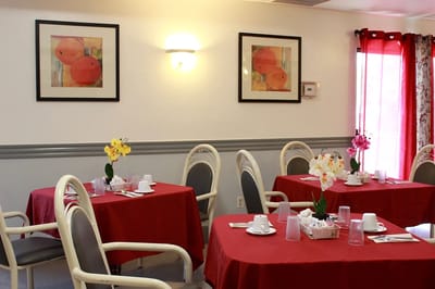 Bright dining area with red tablecloths and floral centerpieces