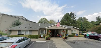 Front entrance of Aegis Living Redmond with residents and flag