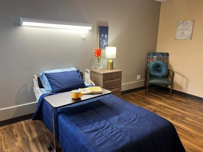 A well-decorated resident room with a bed and chair