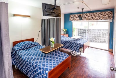 A cozy resident room with two beds and a TV