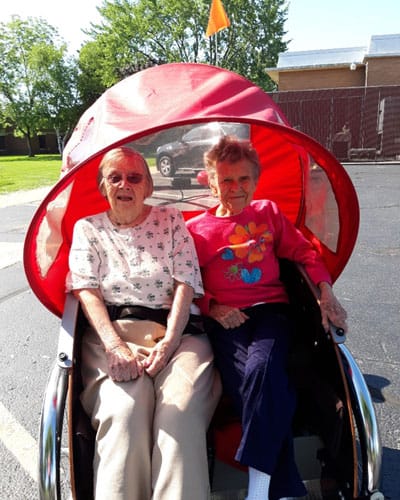 Two residents enjoying a ride in a mobility vehicle outside