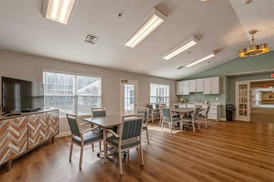 Bright common area with dining tables and a TV