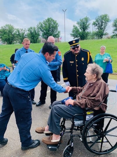 Staff greeting an elderly resident in a wheelchair outdoors