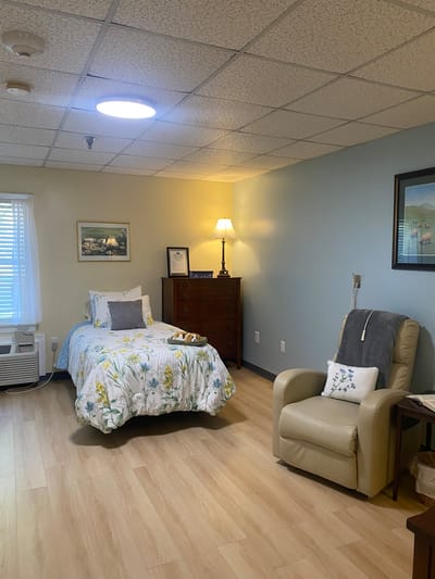 A cozy resident room with a bed and chair