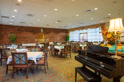 Dining area with tables and piano in a retirement community
