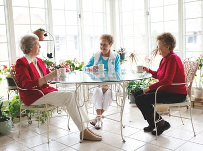 Three residents enjoying tea in a bright common area