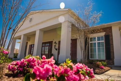 Exterior view of the facility with flowers and sunlight
