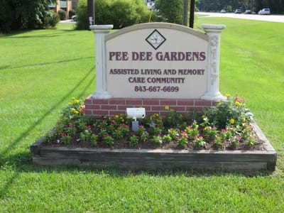 Sign for Pee Dee Gardens with flowers and landscaping