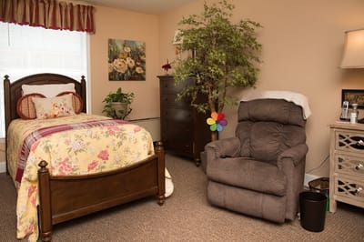 Cozy interior of a resident's room with a bed and recliner