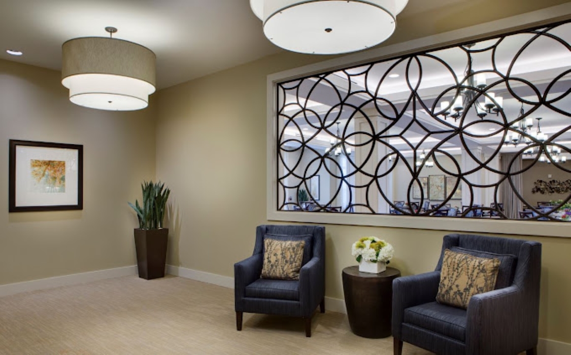 Interior lounge area with chairs and decorative window.