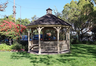 A gazebo in a landscaped garden with blooming flowers