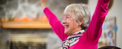 Senior woman joyfully raising her arms in a lively indoor setting
