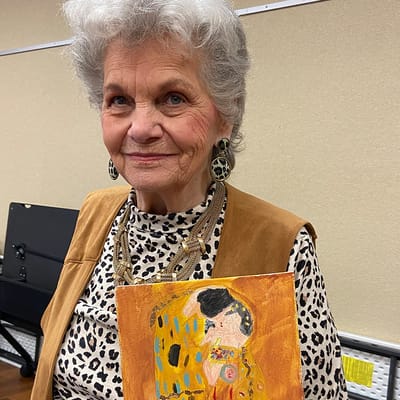 Senior resident holding artwork in a cozy setting
