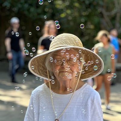 An elderly woman smiling with bubbles around her