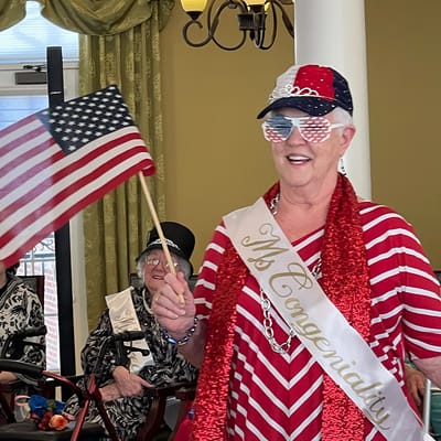 Resident celebrating with patriotic accessories and a flag