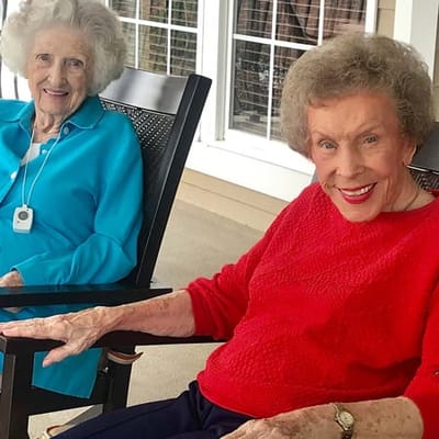 Two smiling residents enjoying a sunny outdoor space