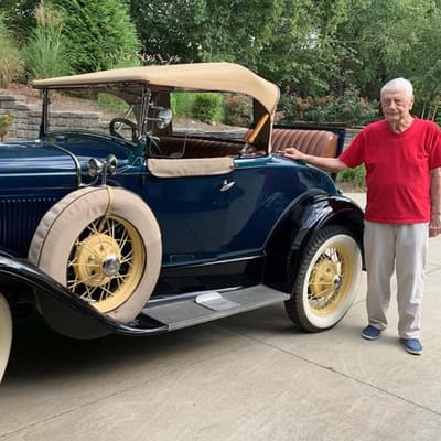Senior resident posing beside a vintage car
