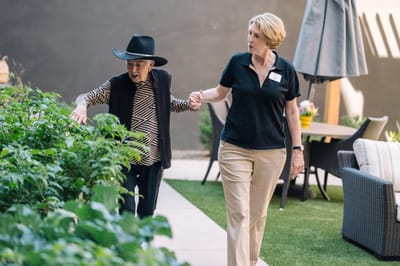 A resident walking in the garden with staff assistance