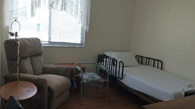 A sparse resident room with a bed and armchair