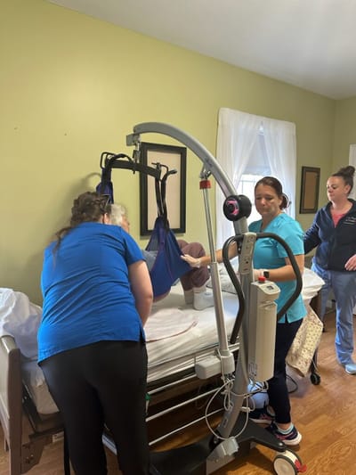 Staff assisting a resident with a lift in a room