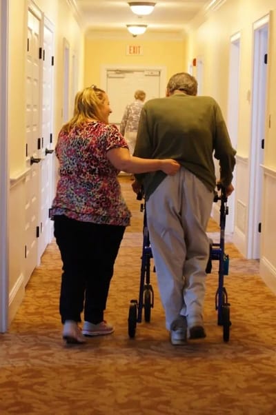 A staff member assisting a resident in a hallway