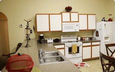 Brightly lit kitchen area with white cabinets and appliances.