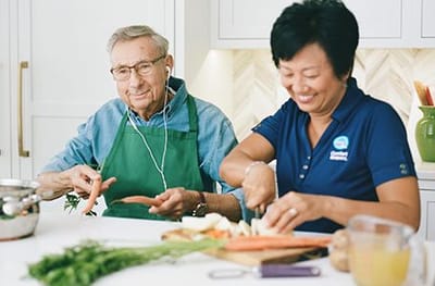 Residents and staff cooking together in a bright kitchen