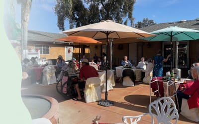 Residents enjoying a meal outdoors under umbrellas