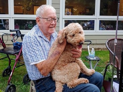 Senior resident enjoying time with a dog outdoors