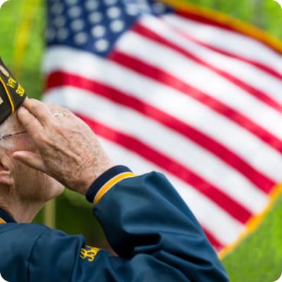 A senior veteran saluting in front of an American flag