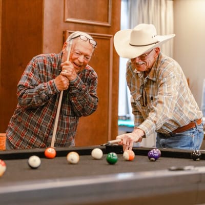 Two residents playing billiards in a common area