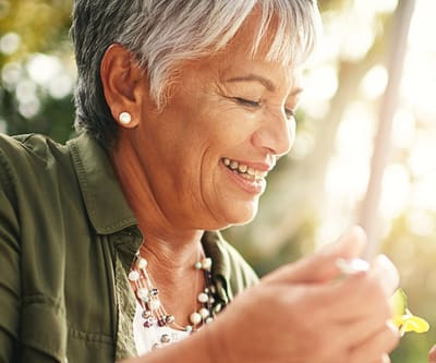 A senior woman smiling while holding flowers