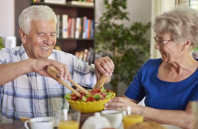 Seniors preparing a salad together at a table