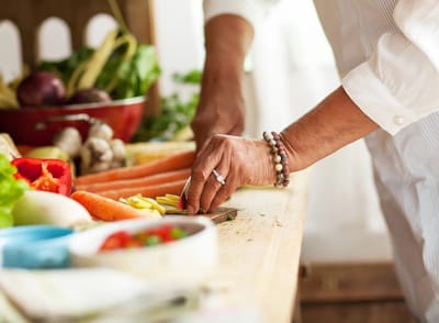 A person's hand preparing fresh vegetables on a wooden table