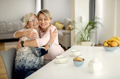Residents sharing a warm embrace at a dining table