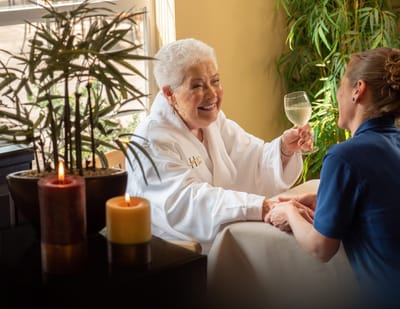 Resident enjoying a beverage with staff in a cozy common area