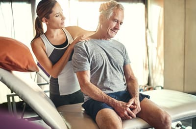 Therapist assisting a senior man during a physical therapy session