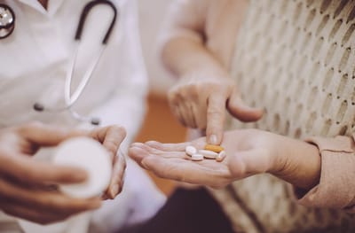 A caregiver showing medication to a resident's hand