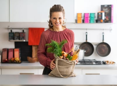 Woman holding a bag of vegetables in a kitchen