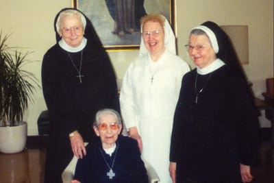 Four seniors in traditional attire smiling together