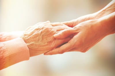Close-up of a caregiver holding a senior's hand